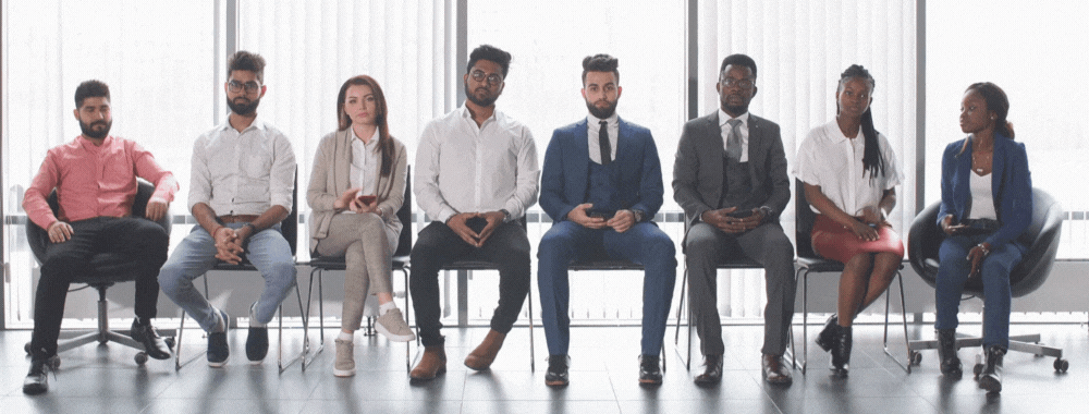 Group of young professionals wait in a line nervously awaiting a job interview